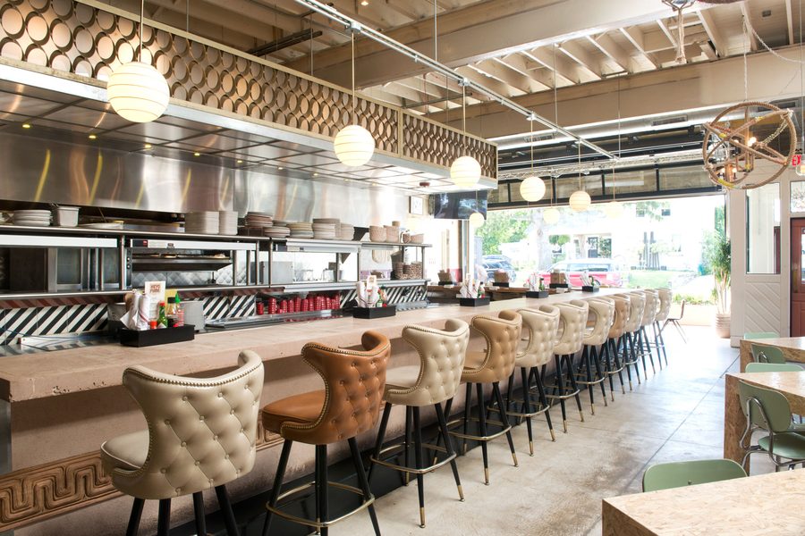 The long counter of tufted stools facing Honcho's open kitchen