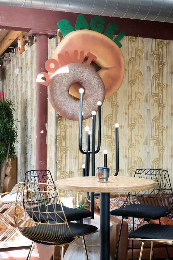 A giant donut sign over cafe tables in the coffeehouse