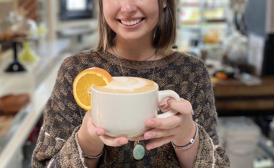 A guest holding a latte with an orange slice