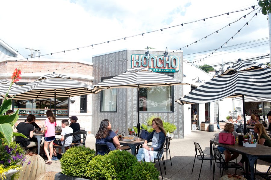 Honcho's patio under striped umbrellas and string lights on a summer afternoon