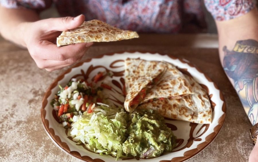 A quesadilla plated with guacamole and pico